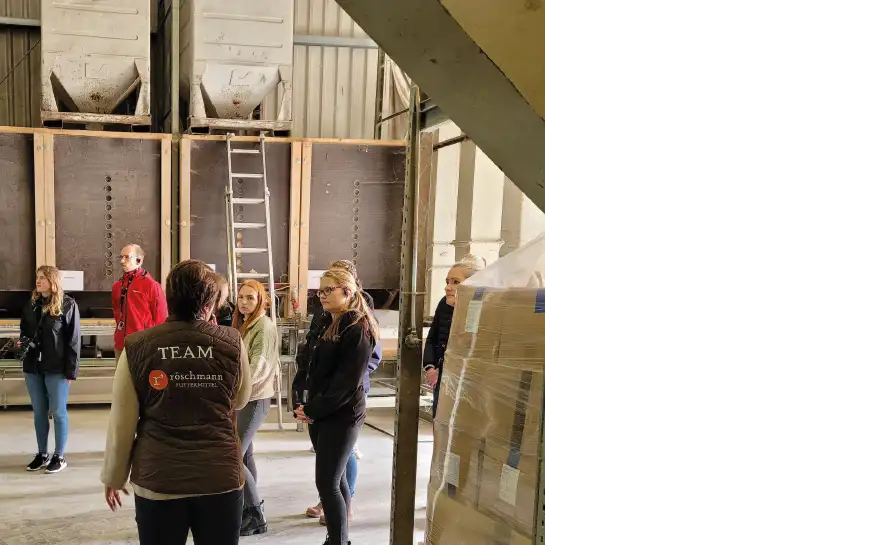 Kristin Röschmann spricht zu einer Gruppe von Menschen in der Produktionshalle von Röschmann in Hadenfeld