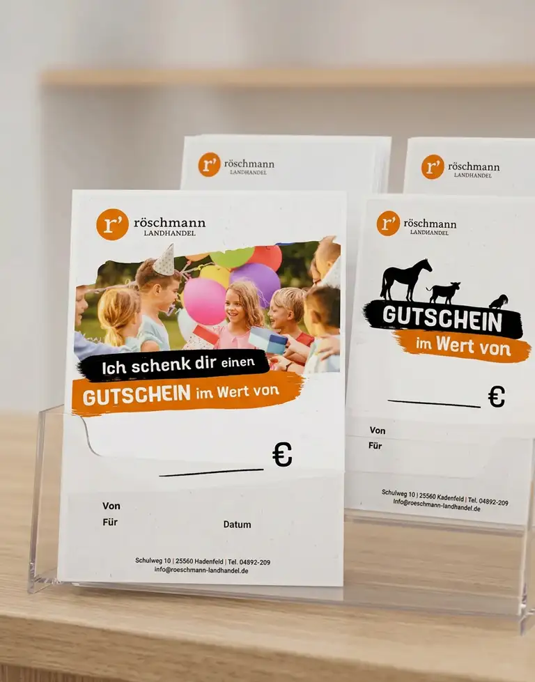 Röschmann-Gutscheine stehen in einem transparenten Display auf einem Holzregal